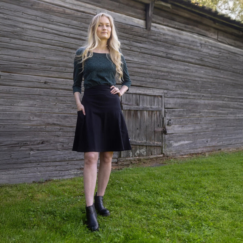 Woman standing in front of a wooden building on grass