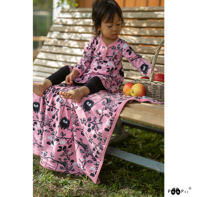 Child eating apples on bench with pink baby blanket
