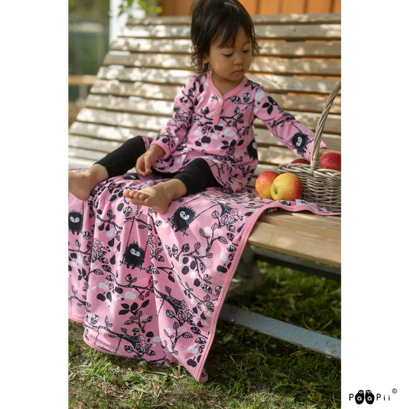 Child eating apples on bench with pink baby blanket