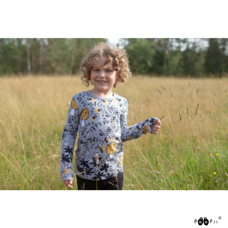 Child in field wearing grey shirt with Mosspath design