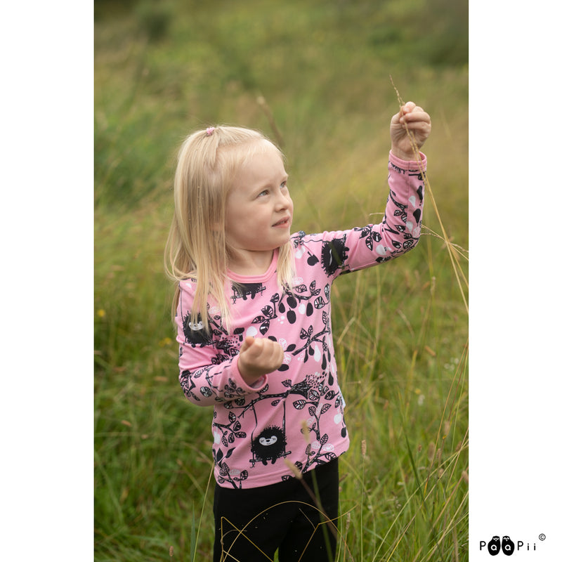Child in grassy field wearing Uljas pink shirt
