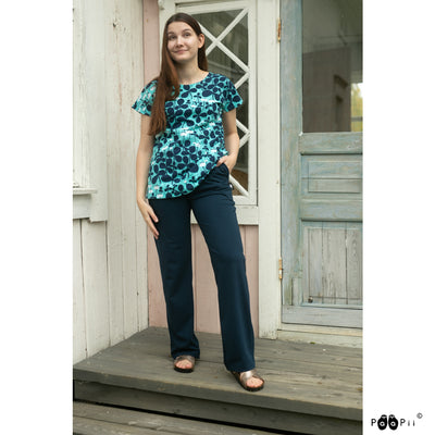 Smiling woman in pants and sandals modeling the PaaPii Vuono Clover Shirt