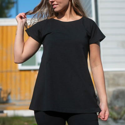 Person wearing a black t-shirt outdoors with a blurred background