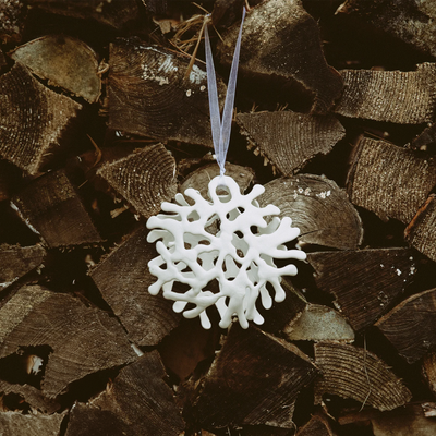 Pentik Lumikide Ceramic Ornament hanging from woodstack