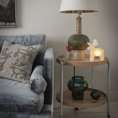 Gray sofa with decorative pillows and a side table with a lamp and vases in a living room setting.