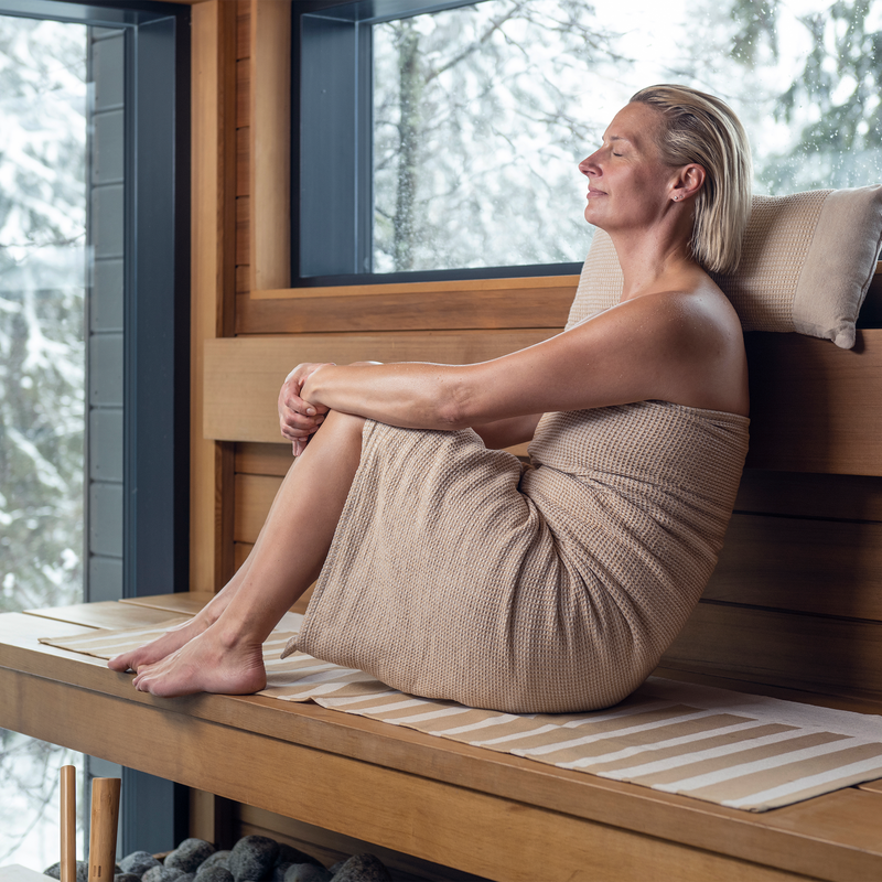 Woman wrapped in Kenno bath towel taking a sauna