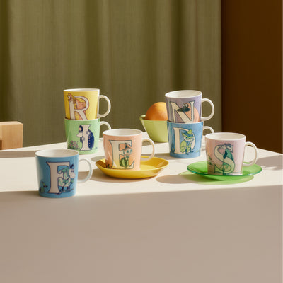 Set of colorful mugs with letter designs on a table