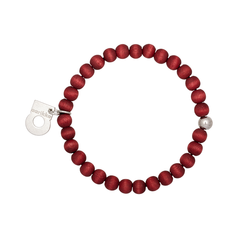 Red beaded bracelet with a silver tag on a white background