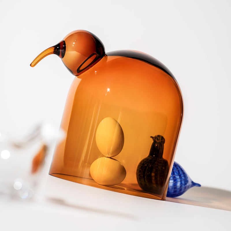 Amber-colored glass sculpture with geometric shapes on a white background
