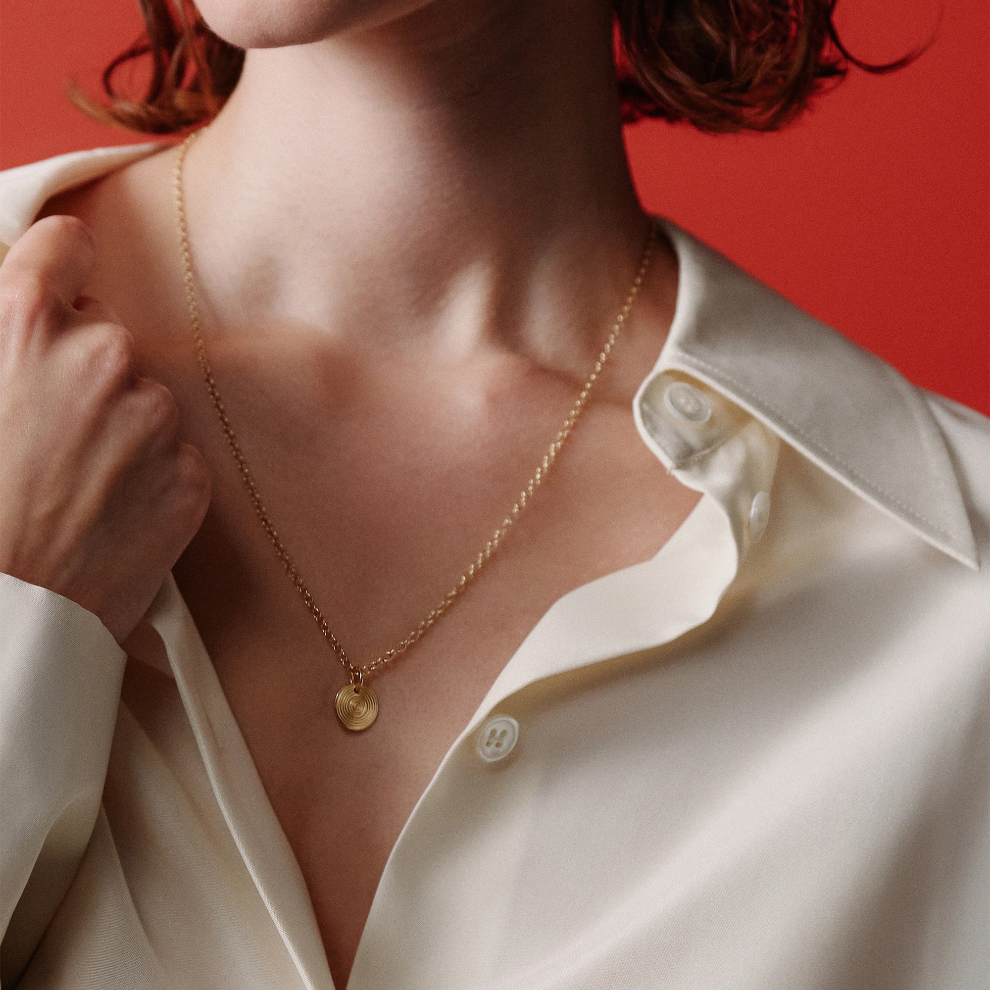Person wearing a gold necklace with a red background