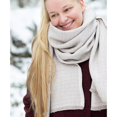 Woman wearing a large beige scarf in a snowy outdoor setting