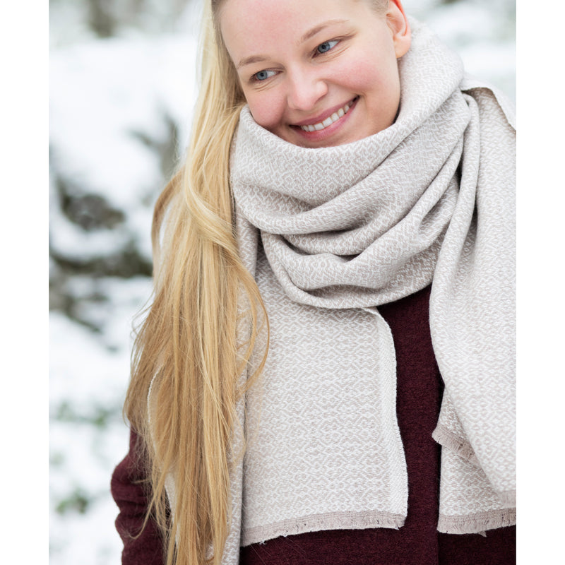 Woman wearing a large beige scarf in a snowy outdoor setting