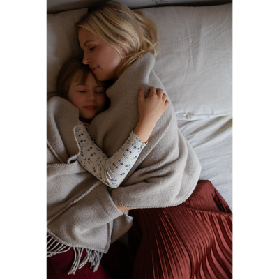 Woman and child hugging under a blanket on a bed