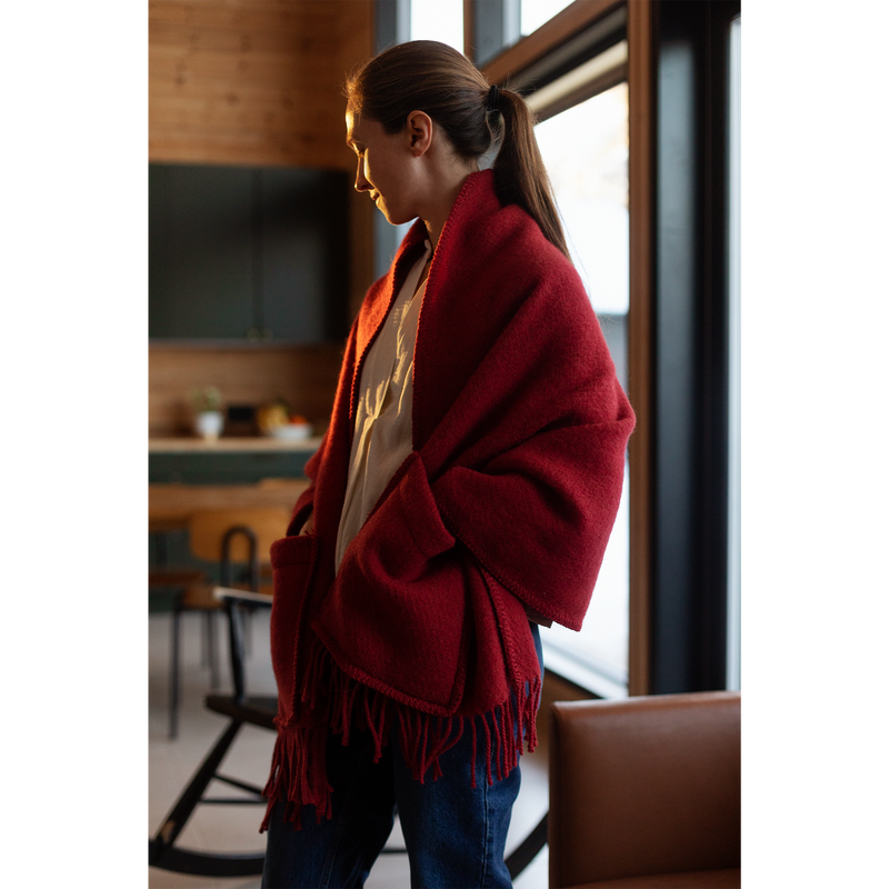 Woman wearing a red scarf in a room with wooden furniture and large windows.