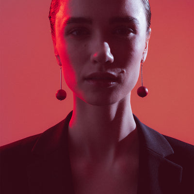 Person wearing earrings with a red filter on a red background