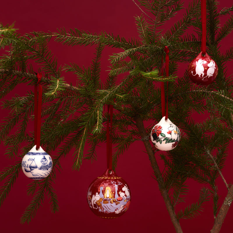 Decorative Christmas ornaments hanging on a tree branch against a red background