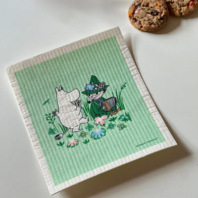 Green towel with cartoon characters on a white surface with cookies in the background