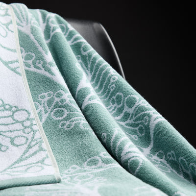 Close-up of a green towel with white embroidery on a black background