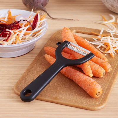 GastroMax Julienne Peeler next to bowl of peeled carrots