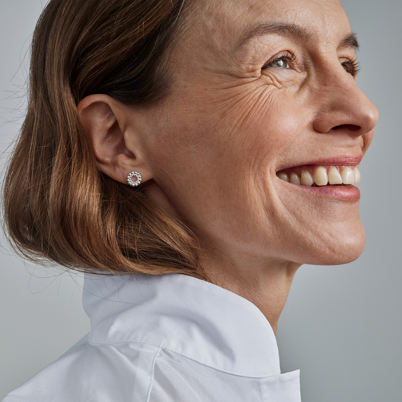 smiling person with brown hair wearing circle of light earring