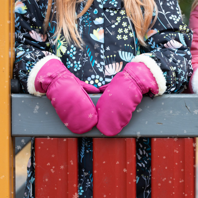 child wearing leather mittens with hands on railing