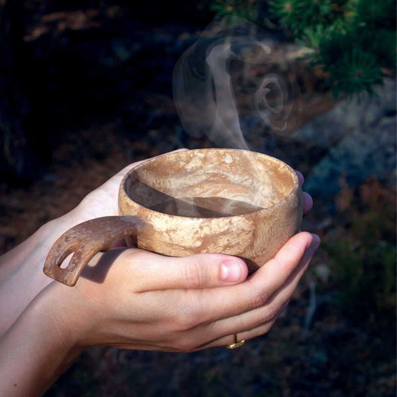 Kupilka cup held in hands with hot beverage inside