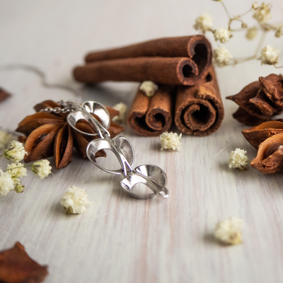 Lumoava Bud Necklace on wooden table with cinnamon sticks