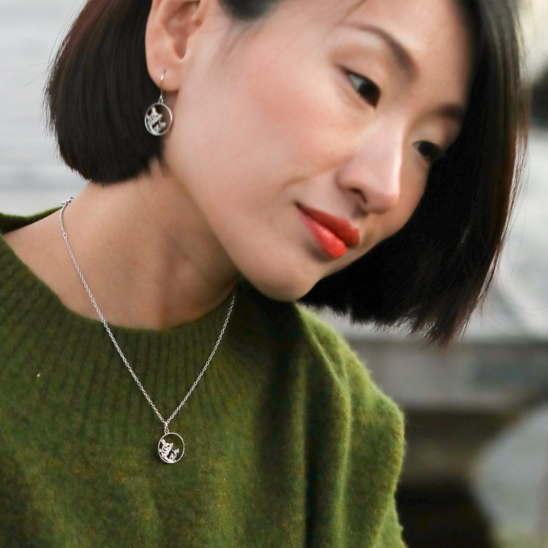 Person in green top looking down while wearing Lumoava Moomin Adventure Necklace