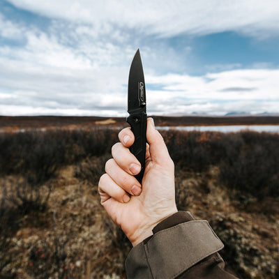 Holding open Marttiini Black 8 Folding Knife in the wilderness