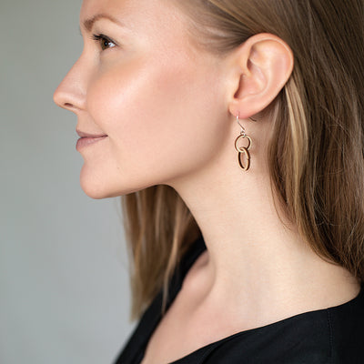 Woman gazing ahead wearing Valona Mini Halo Birch Earrings, Natural