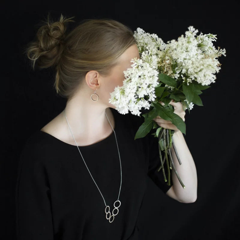 Woman hiding her face with flower while wearing Valona Luna Birch Earrings, Natural