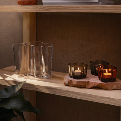 wood shelf holding colored candleholders and clear vase