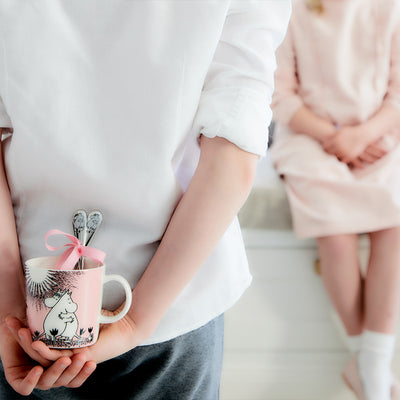 person hiding love mug behind back before gifting