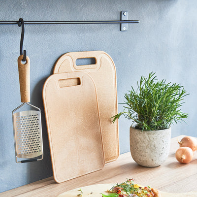 Bio-Based Paddle Grater hanging next to cutting boards