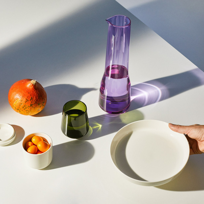 hand placing essence bowl on table next to other dinnerware