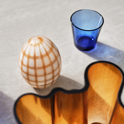 Kartio Ultramarine Blue Tumbler sitting next to glass egg object