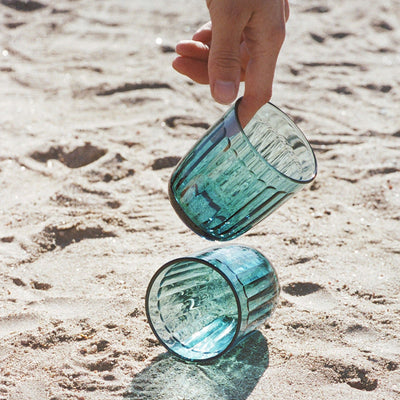 Person picking up Raami tumbler from sand