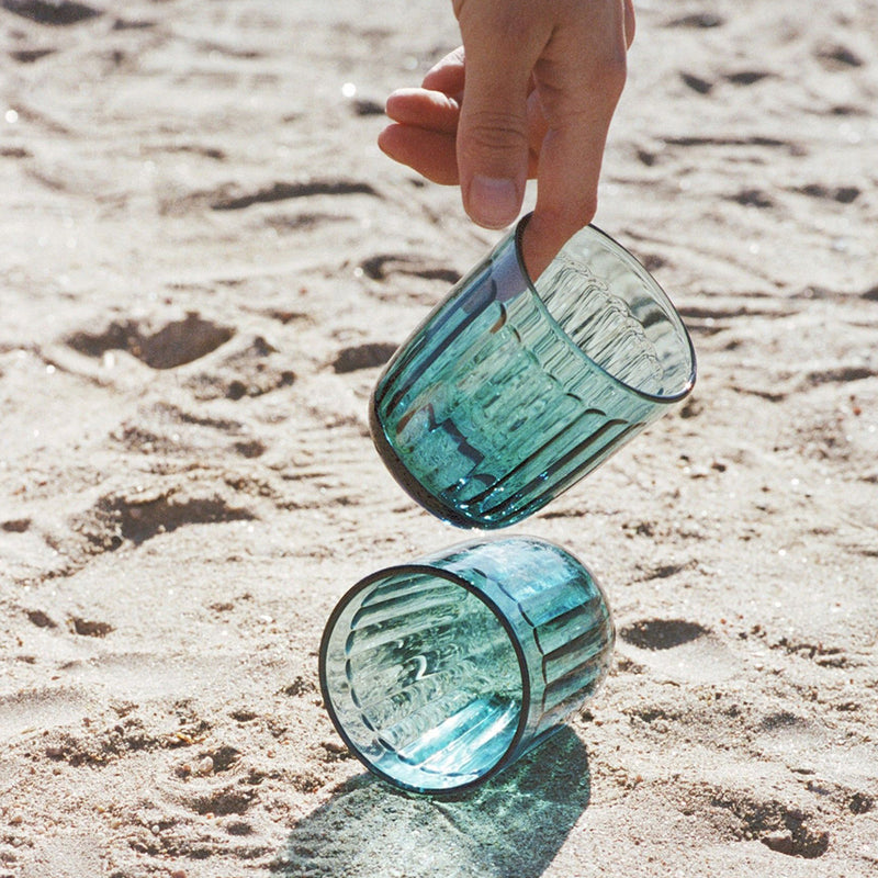 Person picking up Raami tumbler from sand