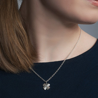 Model in black shirt wearing four leaf clover necklace