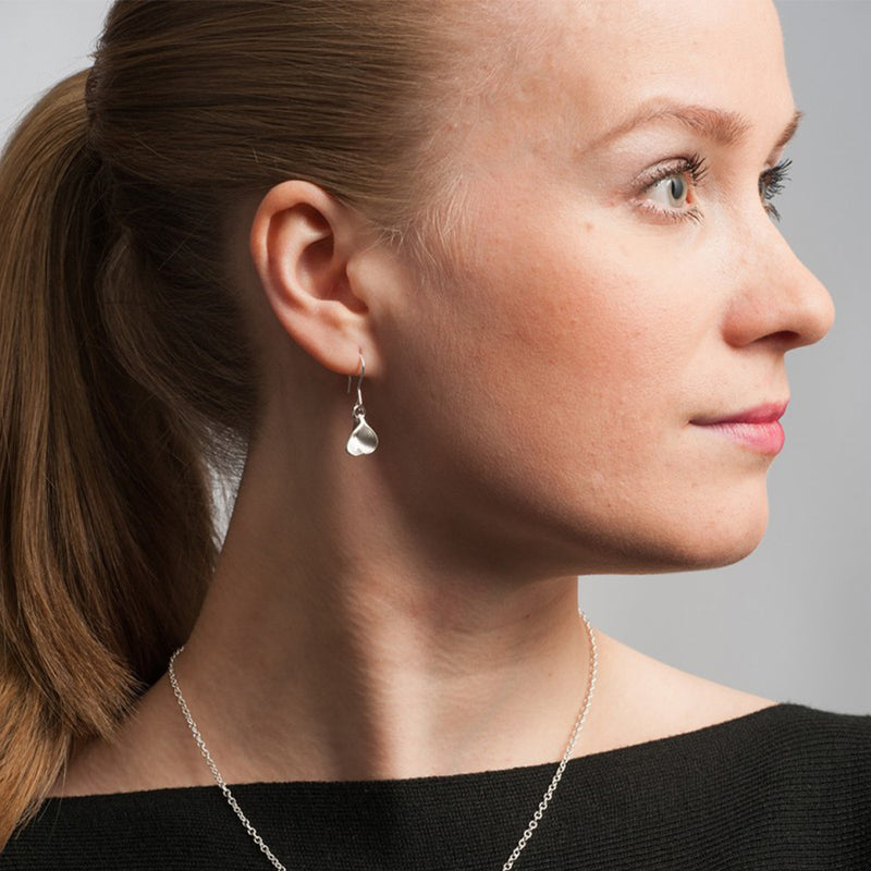 close of person wearing Eira Silver heart earrings