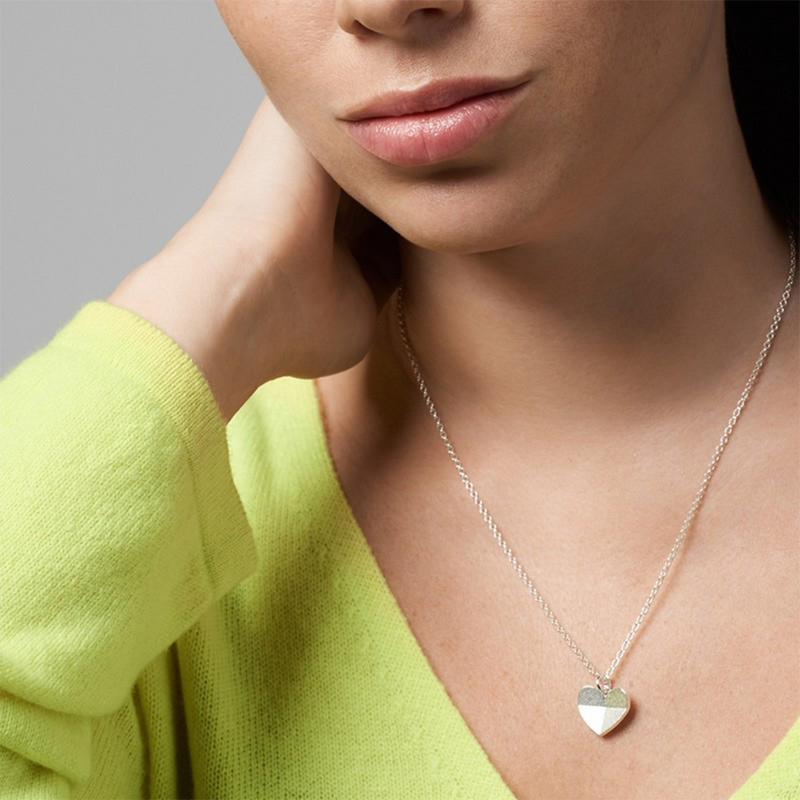 Shy woman in green top wearing Encounters necklace