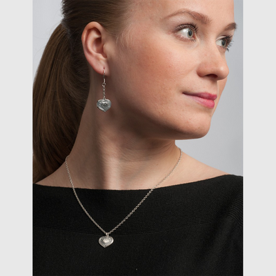 Model looking content wearing eura heart silver necklace and earrings
