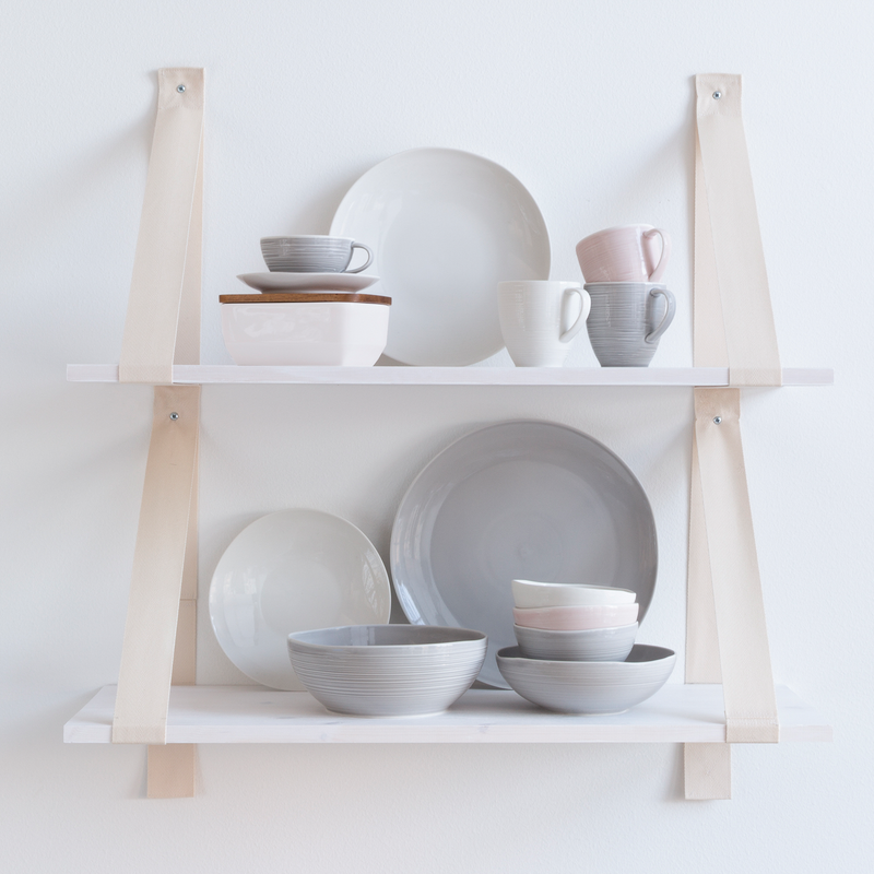 Two floating shelves full of Pentik dinnerware in white, grey and pink colors