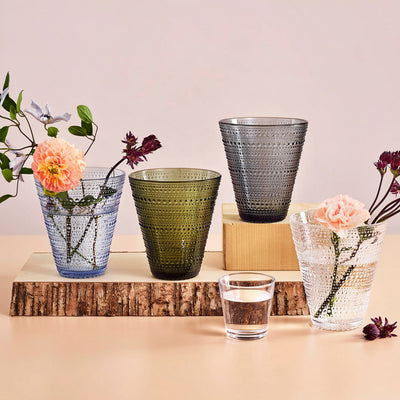 Colored Kastehelmi vases with flowers on wood shelf