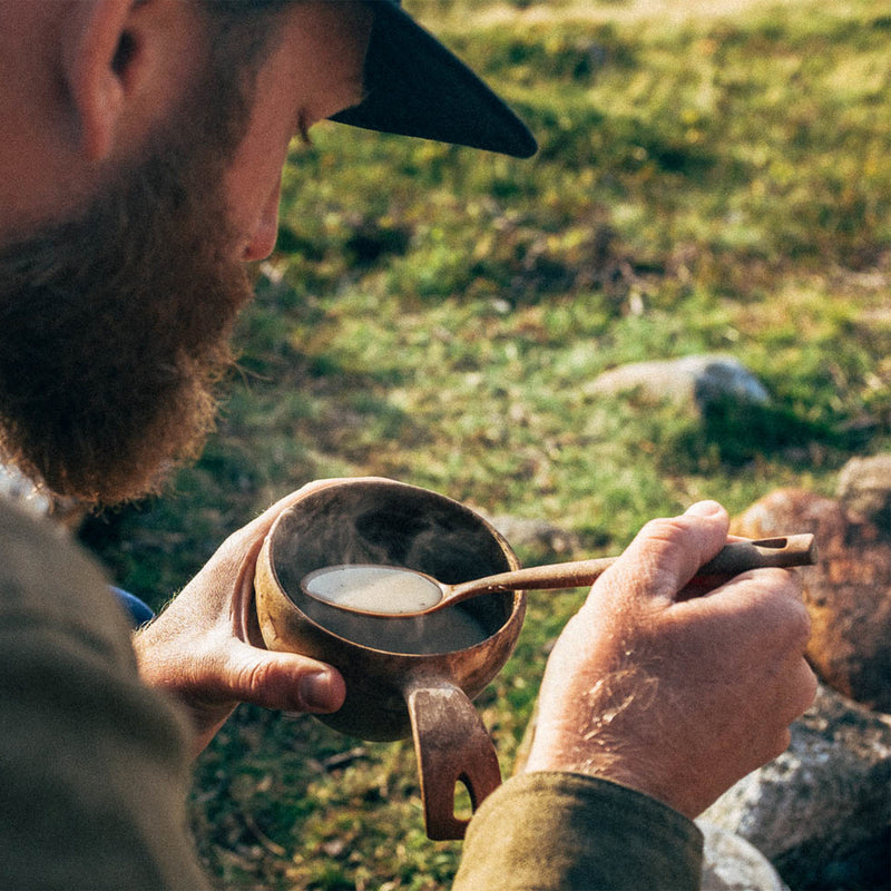 Man eating hot soup out of Kupilka cup outdoors 