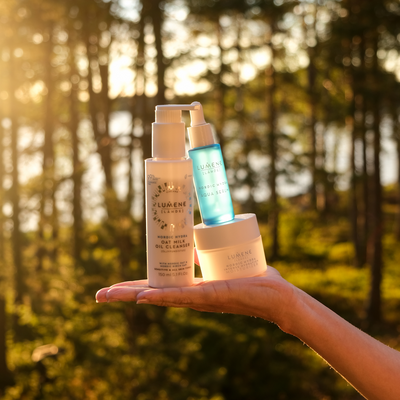 Holding Lumene skincare in woods with sunlight shining down