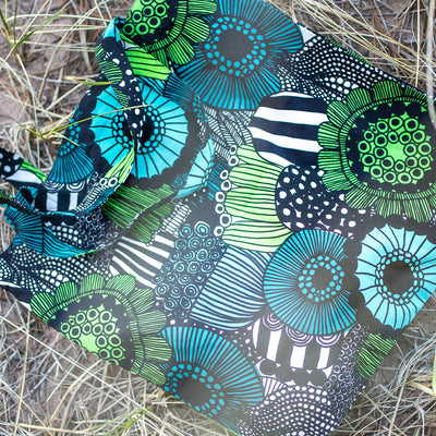 Marimekko Pieni Siirtolapuutarha Cotton Bag laying on sandy beach