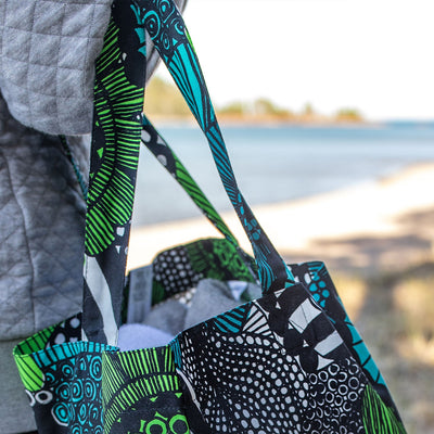 Carrying Marimekko Pieni Siirtolapuutarha Cotton Bag at beach with lake view