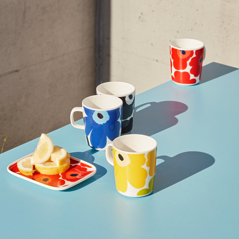 Group of Marimekko Unikko Mugs with rectangular plate on blue tabletop