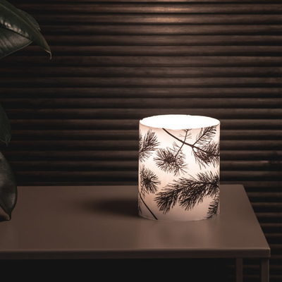 Lit Muurla Pine Large Candle on dark table